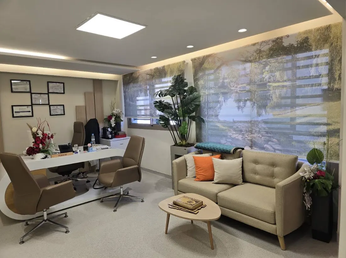 Le bureau du Dr Elalj : fauteuils, canapé et grande fenêtre sur un paysage de lac